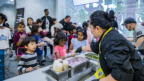 Group of children at an event being served food from Subway