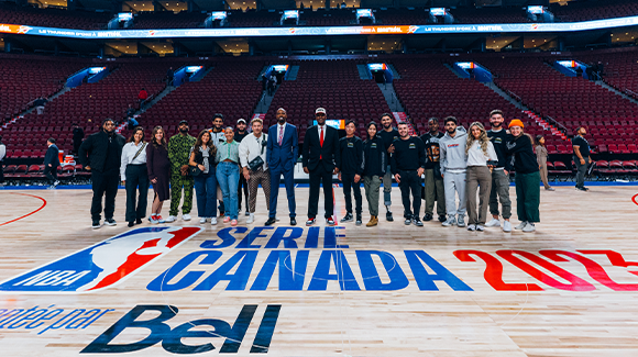 Un groupe posant pour une photo, sur un terrain de basketball avec la marque de la NBA. 